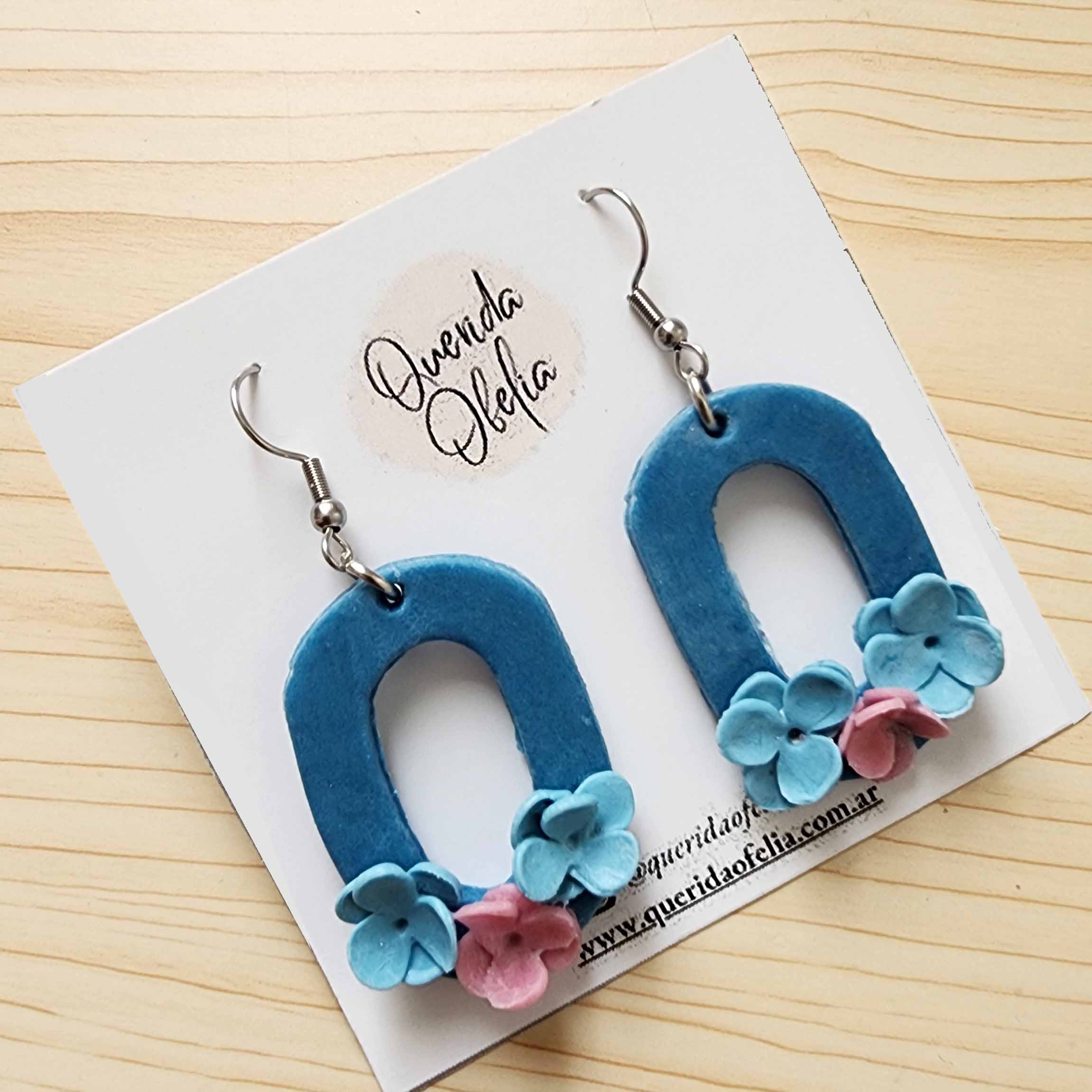 Aros Rectangulares Artesanales Hipoalergénicos Aros hechos a mano de acero quirúrgico hipoalergénico con diseño rectangular y tres flores de porcelana fría, ideales para mujeres que buscan bijouterie exclusiva.