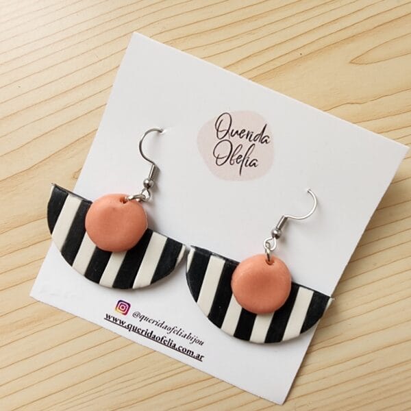 Par de aros geométricos semicirculares de bijouterie, hechos a mano en porcelana fría con rayas blancas y negras y un toque de color, con base de acero quirúrgico hipoalergénico. Ideales para mujeres que buscan un accesorio exclusivo y personalizado.