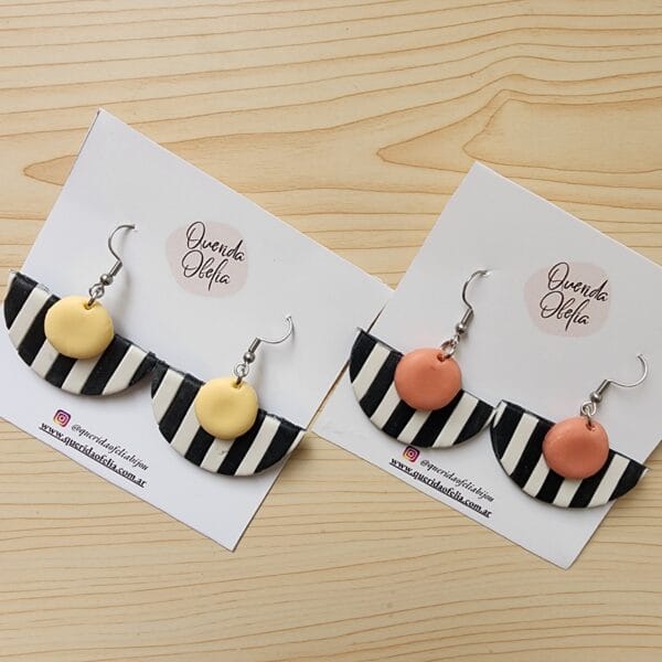 Par de aros geométricos semicirculares de bijouterie, hechos a mano en porcelana fría con rayas blancas y negras y un toque de color, con base de acero quirúrgico hipoalergénico. Ideales para mujeres que buscan un accesorio exclusivo y personalizado.