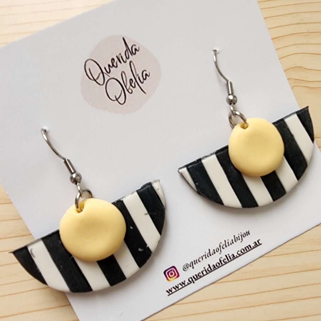 Par de aros geométricos semicirculares de bijouterie, hechos a mano en porcelana fría con rayas blancas y negras y un toque de color, con base de acero quirúrgico hipoalergénico. Ideales para mujeres que buscan un accesorio exclusivo y personalizado.