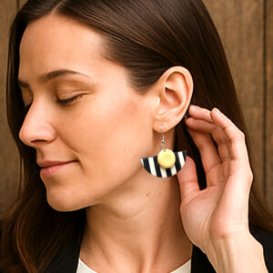 Par de aros geométricos semicirculares de bijouterie, hechos a mano en porcelana fría con rayas blancas y negras y un toque de color, con base de acero quirúrgico hipoalergénico. Ideales para mujeres que buscan un accesorio exclusivo y personalizado.